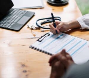 a person writing on a clipboard on a desk