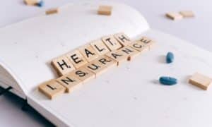 a notebook with board game wooden letters that spell out "health insurance"