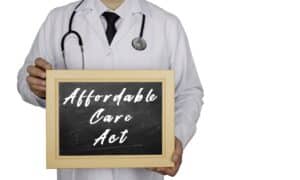 a doctor holding a chalkboard that says "affordable care act"