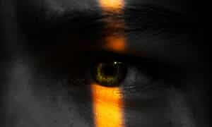 a man's eye illuminated by a strip of light, accentuating the colors in it