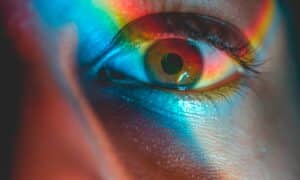 a person's eye being lit up by a rainbow