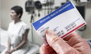 a woman sitting on a hospital bed and an insurance card being held up in front of her
