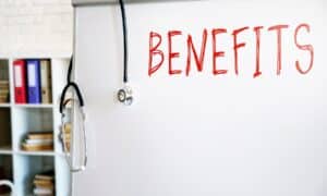 a whiteboard with a stethoscope over the corner and "benefits" written in red marker