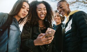 a group of college students looking at a phone and smiling