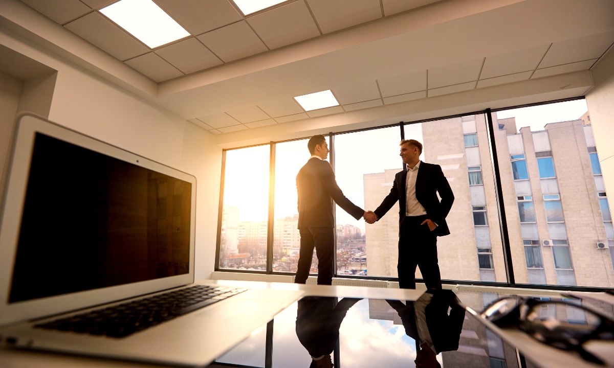 two businessmen shaking hands in a highrise