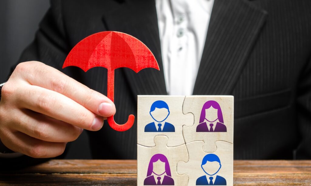 a person holding a tiny umbrella over tiny figures on a puzzle square to imply protecting or shielding employees will raise employee satisfaction rates