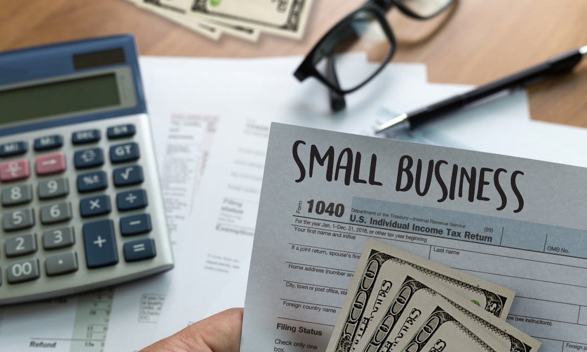 a calculator and paperwork and cash and a paper that says "small business" at the top