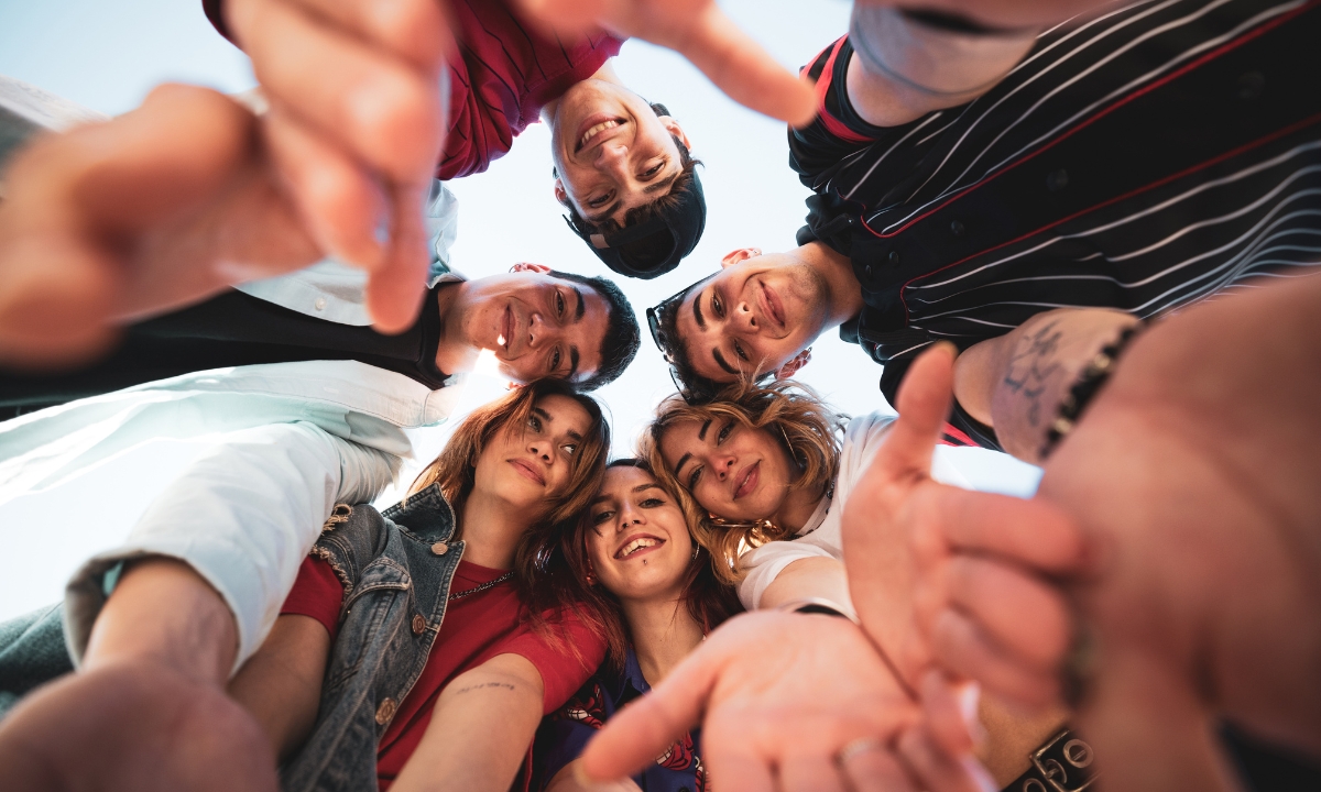 a group of gen z people in a circle their hands down towards the camera