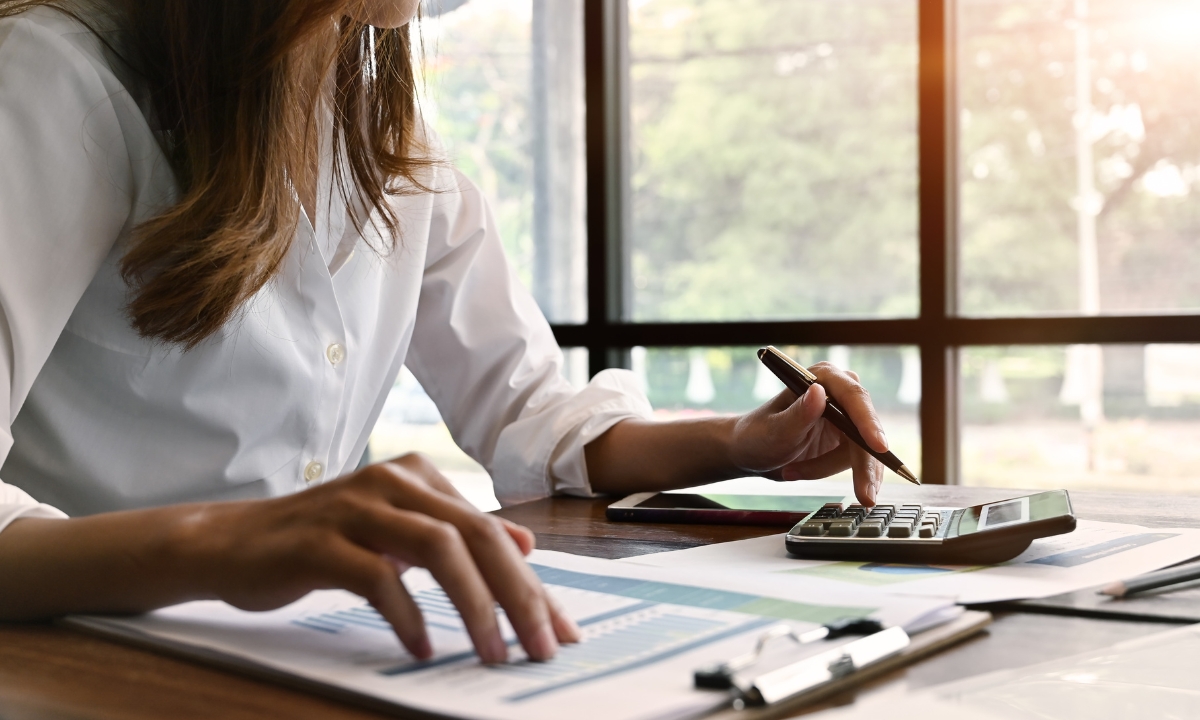 a person at a desk using a calculator and a clipboard